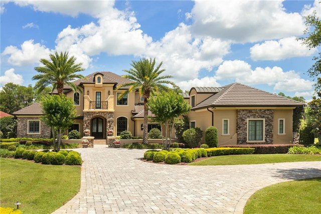 Mediterranean-style estate home in Windermere, Florida with paver driveway and mature palm landscaping